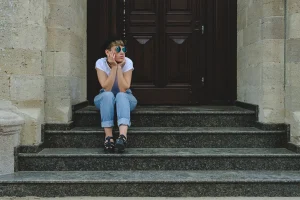 fille assise sur les marches d'escalier à l'entrée de la porte de l'immeuble